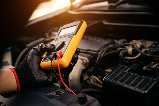Car mechanic technician use measuring tool to check electrical voltage battery low energy problem for car care service maintenance and re charger or jump start or change new battery replacement.