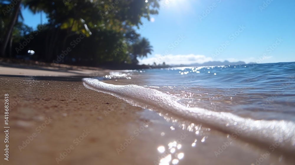 Aufkleber Close-up view of a sandy beach with gentle waves and sun reflections. Shallow depth of field shows details of the wet sand and water. Palm trees and trees on the background in sunny day