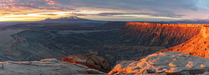 Naklejka premium The Henry Mountains covered in snow rise above the Utah Badlands on this brisk winter morning atop North Cainville Mesa during a beautiful sunrise.