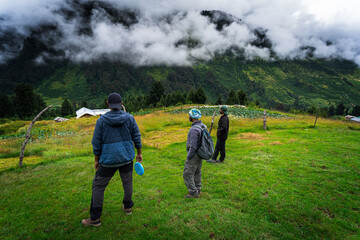  friends enjoying a game of flying discin scenic mountain landscape. Surrounded by misty clouds,...