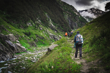 Fototapeta premium Group of trekkers with hiking backpacks on beautiful mountain landscape background. Climbers hike to mountains. Group of hikers walking in mountains 