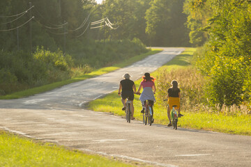 Obraz premium Group Cycling Along a Scenic Road During a Sunny Summer Day