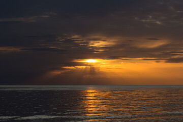Golden Sunset Over Calm Waters with Radiant Sun Rays in the Sky