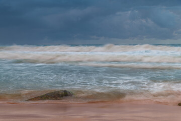 Sunrise at the seaside with rocks and rain clouds