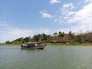 A boat peacefully anchored on the water, reflecting the sunlight and nearby landscape.