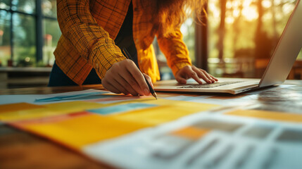 Freelance graphic designer using drawing tablet and laptop, modern creative workspace, daylight and sketch paper on desk