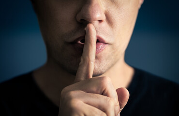 Quiet and silence! Secret of a man. Hush. Finger and mouth. Shh. Silent confidential gesture. Lips sealed. Freedom of speech, censorship, taboo or gossip concept.