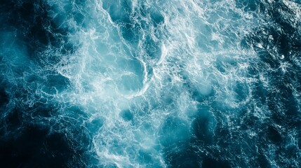 Aerial view of churning ocean water with white foam and shades of blue