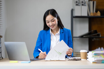 Businesswoman working with financial documents on laptop in office.