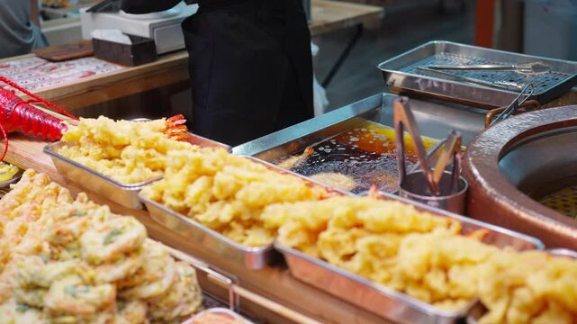Small business local street food vendor preparing typical Japanese food Tempura selling to customer at street market in Japan. People enjoy travel and eating Japanese street food on holiday vacation.