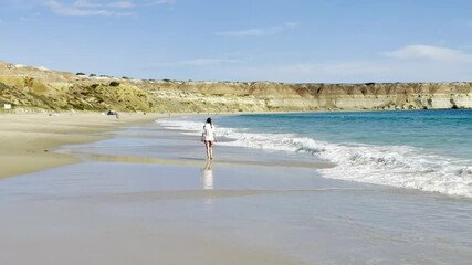 A girl enjoys a leisurely walk on the beautiful Maslin Beach with its turquoise clear waters and massive cliffs. Fleurieu Peninsula, Onkaparinga, Adelaide, South Australia