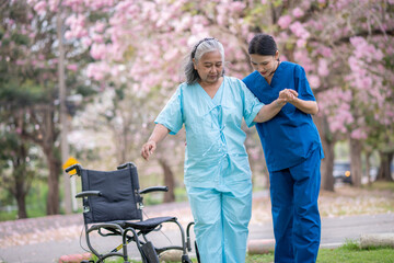 Nurse caregiver with elderly woman enjoying beneath blooming trees. suggesting in healthcare...