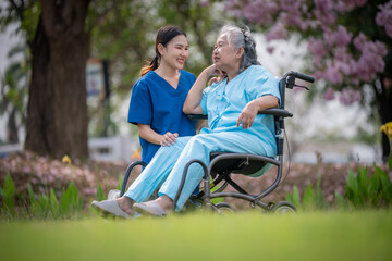 Nurse caregiver with elderly woman enjoying beneath blooming trees. suggesting in healthcare...
