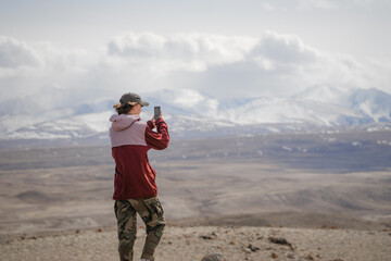 takes pictures of mountains on his phone