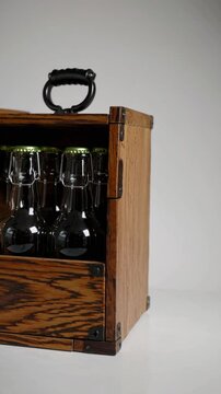 Antique wooden beer carrier with swing top bottles on white.
