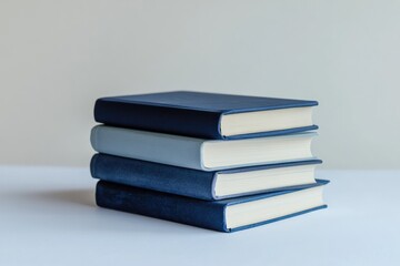 Stack of four hardcover books in varying shades of blue, arranged neatly on a white surface.