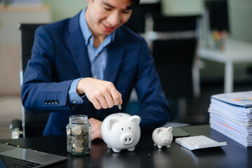 Smiling businessman saves money with piggy bank and coins; ideal for themes of finance, savings,...
