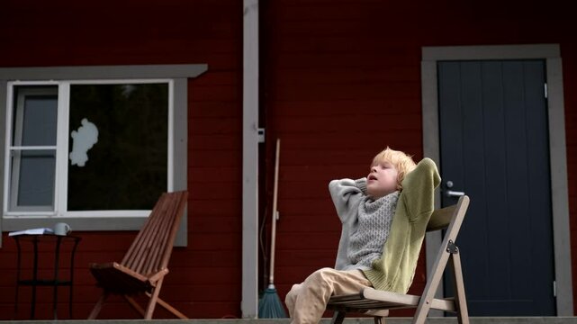 boy sitting on a chair on the terrace of a house