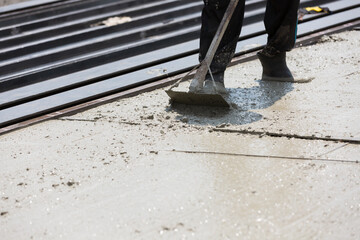 Construction worker plastering wet concrete at precast concrete wall construction site. Worker or mason working or making smooth surface of concrete at site work