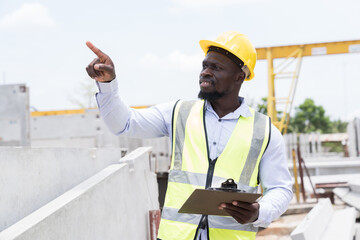 Engineer, Construction site. Foreman builder man working and inspecting structure of precast concrete wall at construction site. African American foreman construction man working at site work