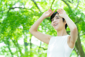 緑の中でスキンケアをするショートヘアの若い女性