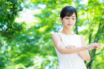 緑の中でスキンケアをするショートヘアの若い女性