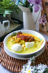 Lontong, a traditional Southeast Asian dish of compressed rice cakes in rich coconut curry, served with lodeh, sambal kacang, sambal tumis, hard-boiled eggs, and fresh vegetables on a decorative plate