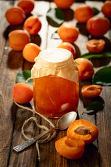 Apricot jam and fresh fruit on an old wooden table.