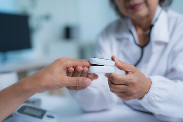 Close-up view of a doctor measuring a patient's oxygen saturation with a pulse oximeter in a...