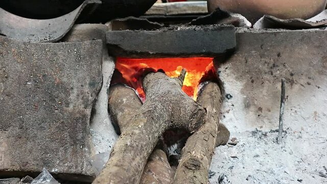 Close up of cooking using firewood as the main fuel on a traditional stove in an old kitchen in the village.
