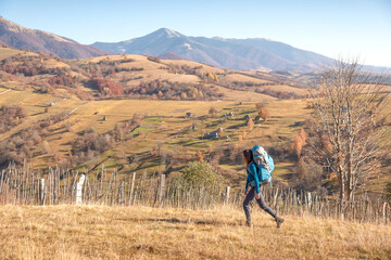 Woman backpacking in open mountain landscape during fall season, surrounded by panoramic alpine...