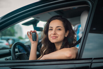 Happy Caucasian female car driver showing new car keys while sitting at driver seat. Lifestyle, transportation, sale, ownership concept