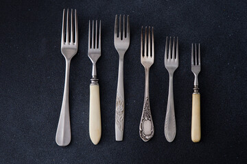 Forks on a black background. Set of old different cutlery for food. Silver fork.