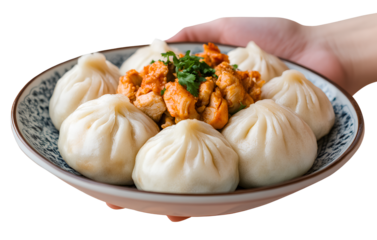 Hand holding steamed buns with chicken and sweet potato filling, plate on a transparent background