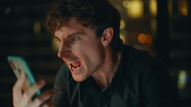 Mad executive yelling mobile phone at night office closeup. Portrait angry man