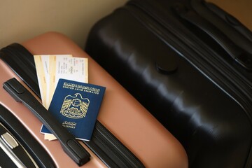 United Arab Emirates UAE passport with tickets lies on touristic suitcase close up in airport hall