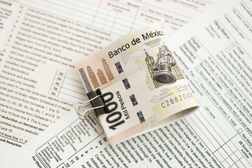 Mexican pesos money bills in big amount lies on table with tax forms close up
