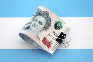 Argentine pesos money bills in big amount lies on Argentina flag close up