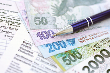 Argentine pesos money bills in big amount lies on table with pen and tax forms close up
