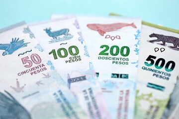 Argentine pesos money bills in big amount lies on teal color table close up