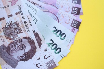 Mexican pesos money bills in big amount lies on yellow color table close up
