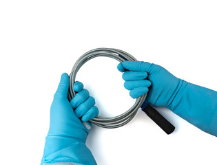 Metal drain auger tool isolated, plumbing snake or cable in hands in blue glove on white background