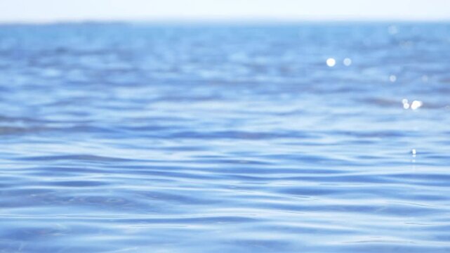 Calm blue sea surface and horizon, slow motion shallow dof 