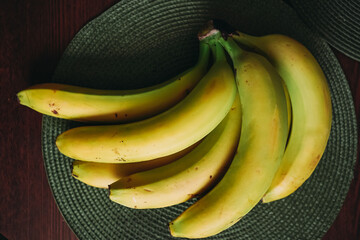 Bananas on a wooden table. Fresh, yellow, green bananas on the table on a green napkin. Ripe bananas close-up