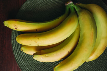 Bananas on a wooden table. Fresh, yellow, green bananas on the table on a green napkin. Ripe bananas close-up © Svetlana
