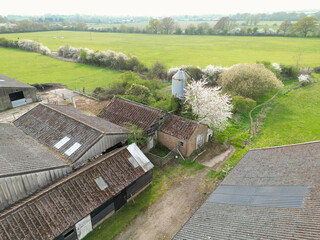 Aerial view of a large and mainly derelict dairy farm seen in rural Britain. Notice the tall grain...