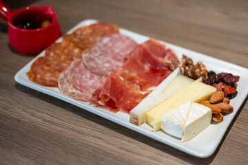 Cold cuts platter, variety of sliced meat and cheese with olives and nuts
