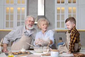 Grandparents and their grandson cooking together at table in kitchen