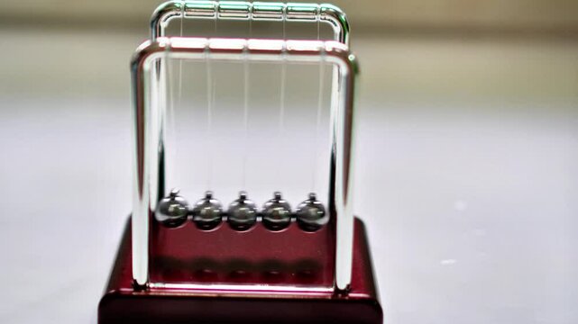 Video footage of a  Newton's cradle  swinging back and forth on a desk to create a relaxing feeling.