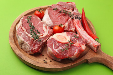Pieces of raw beef, spices and products on green table, closeup